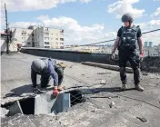  ?? DIMITAR DILKOFF TNS ?? Members of a demining team of the State Emergency Service of Ukraine check the roof of a residentia­l building for unexploded devices following Russian shelling in Kharkiv, eastern Ukraine, on Thursday.