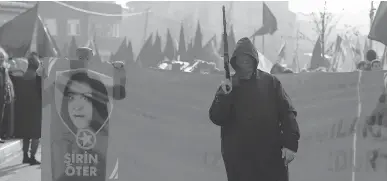  ?? EMRAH GUREL/THE ASSOCIATED PRESS ?? A masked and armed man walks during the funerals on Wednesday of Sirin Oter and Yeliz Erbay, two women killed during security operations on Tuesday in Istanbul. Turkish security forces have killed 145 Kurdish rebels in a week.