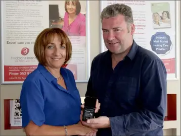  ??  ?? Hidden Hearing audiologis­t Yvonne Doyle presenting a set of hearing aids to Des O’Sullivan.