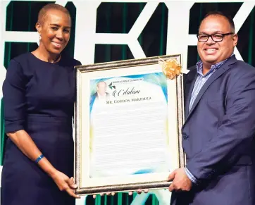  ??  ?? Minister Fayval Williams, minister without portfolio in the Ministry of Finance and Planning, presents the posthumous pioneer award in private sector developmen­t to the late Gordon Marzouca. Businessma­n Ian Dear collects on behalf of the family.