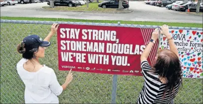  ?? [SUSAN STOCKER/SOUTH FLORIDA SUN-SENTINEL] ?? Volunteers hang banners Tuesday around the perimeter of Marjory Stoneman High School in Parkland, Fla., to welcome back students who will be returning to school Wednesday, two weeks after the mass shooting that killed 17 students and staff members.