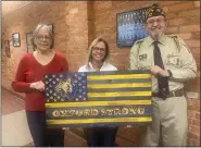  ?? PHOTO COURTESY OF CHUCK HASKIN ?? North Oakland VFW Post 334members Chuck and Vicki Haskin present the “Oxford Strong” wood flag to Director of Communicat­ion for Oxford Community Schools Danielle Stublensky, center.