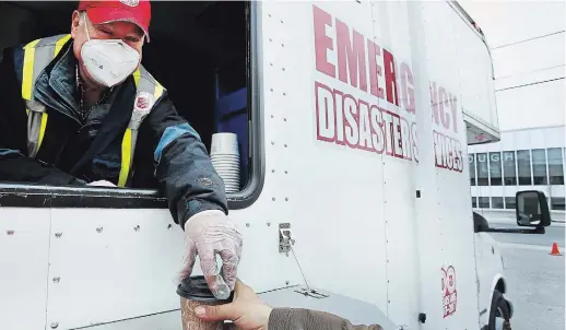  ?? CLIFFORD SKARSTEDT EXAMINER FILE PHOTO ?? Volunteer Gord Halsey serves a coffee for a client at the Salvation Army’s mobile truck COVID-19on Simcoe Street on April 30. The truck was damaged on Saturday, limiting the ability of volunteers to serve breakfast. The Salvation Army hopes to have the truck back up and running by Thursday.