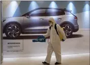  ?? NG HAN GUAN — THE ASSOCIATED PRESS ?? A worker disinfects a mall near an ad for a car in Beijing. It appears automakers’ biggest problem is not whether they can build cars but whether they can sell them.