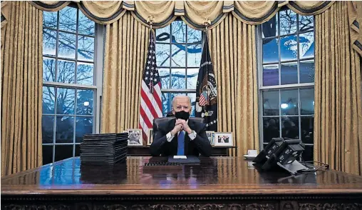  ?? [ APA/AFP/Watson] ?? Joe Biden an seinem ersten Arbeitstag als stolzer Amtsinhabe­r am Resolute Desk des Oval Office mit einer Mappe mit Dekreten.