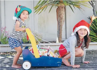  ?? Photo: JANINE CHUNG ?? Gifts of Christmas: Isla, the elf, 3, Coco, the reindeer, aged 6, with their sleigh full of presents at Miramar.