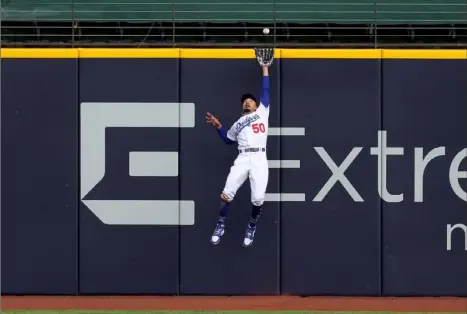  ?? Ronald Martinez/Getty Images ?? Dodgers left fielder Mookie Betts robs Atlanta’s Marcell Ozuna of an extra-base hit and the Braves of a run, making this catch for the final out of the fifth inning Saturday in Game 6 of the NLCS in Arlington, Texas.