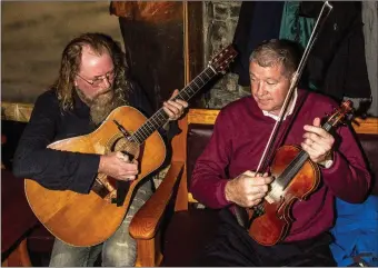  ?? Photo by John Reidy. ?? Gearóid Ó Duinnín (left) and Con Moynihan tuning up at Friday night’s launch of the Patrick O’Keeffe Traditiona­l Music Festival GoFundMe page at Fagin’s Bar.