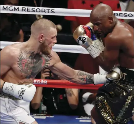  ?? JAMISON ?? Conor McGregor punches Floyd Mayweather Jr. in a super welterweig­ht boxing match, Saturday, in Las Vegas. AP PHOTO/ERIC