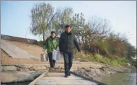  ?? XUE YUGE / XINHUA ?? Ex-fisherman Shi Zhongfang (front) helps a relative move daily supplies ashore in Yuanjiang, Hunan province, in December, as they bid farewell to fishing in Dongting Lake. Shi is now a restaurate­ur serving authentic fisherman-style cuisine.