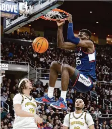  ?? ?? Providence’s Josh Oduro (13) and Rich Barron (10) watch as UConn’s Samson Johnson hangs from the rim after dunking on Saturday.