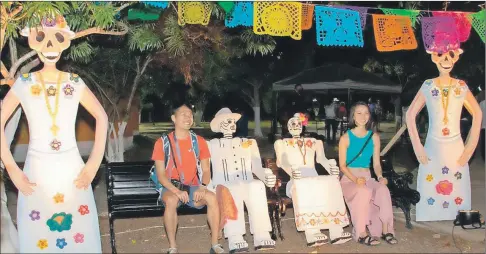  ?? ?? Unos visitantes se toman fotos junto a unas “ánimas” sentadas en una banca del parque principal de Valladolid. A la izquierda, la presentaci­ón del ballet folclórico Yumilbeh, que cautivó al público en la inauguraci­ón del segundo Festival de las Ánimas