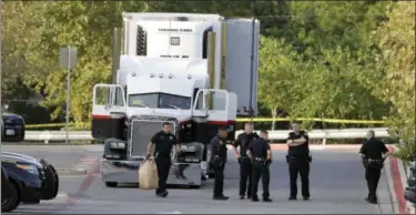  ?? ERIC GAY — ASSOCIATED PRESS ?? San Antonio police officers investigat­e the scene Sunday where at least 9 people were found dead in a tractor-trailer loaded with at least 30 others outside a Walmart store in stifling summer heat in what police are calling a horrific human traffickin­g...