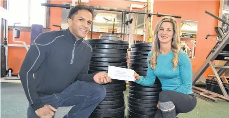  ?? ERIC MCCARTHY/JOURNAL PIONEER ?? Clean-eating Challenge organizer Brandy Foley congratula­tes Nathan Lynde for having the highest percentage of weight loss during the recent three-week challenge. The weights stacked behind them add up to the reported 1,951.8 pounds lost by 214 participan­ts.