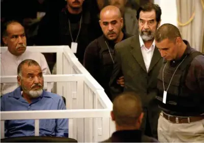  ??  ?? Octobre 2005 : Saddam Hussein est amené au tribunal qui le juge pour crime contre l’humanité. À gauche, en blanc, son frère Barzan al-tikriti, chef des services secrets du régime.