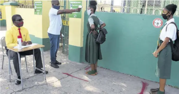  ?? (Photo: Naphtali Juinior) ?? Chevoy Matrin (left), guidance counsellor at St Jago High School, records attendance of students while security officer Rennaldo Brown checks their temperatur­e before they enter the school compound in St Catherine, in this June 8, 2020 file photo. Instead of face-to-face classes students will be engaging online classes, and in some cases will have lessons delivered by television.