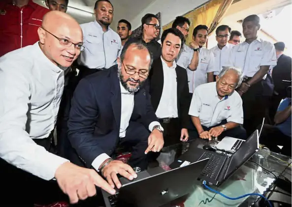  ??  ?? (From left) Al-Ishsal and Gobind trying out the high-speed broadband service after the launch of the Government’s National Fiberisati­on and Connectivi­ty Plan in Jasin, Melaka. Looking on are Kerk (second from right) and Moggie (right).