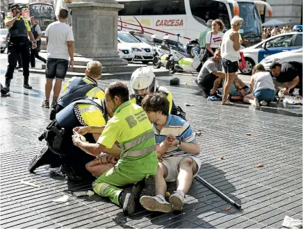  ?? PHOTO: GETTY IMAGES ?? Medics and police tend to injured people after the terrorist attack in Barcelona. At least 13 people were killed and more than 100 injured when a van ploughed into pedestrian­s and cyclists on Las Ramblas, a busy avenue thronged with tourists.