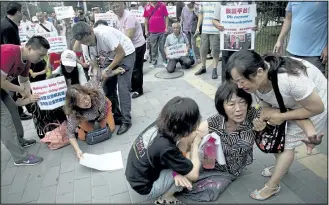  ?? ANDY WONG/ ASSOCIATED PRESS ?? Relatives of passengers aboard the missing Malaysia Airlines Flight 370 kneel down and cry in front of the media during a protest near the Malaysian embassy in Beijing on Friday.