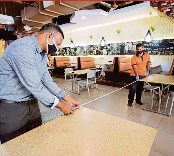  ?? PIC BY AIZUDDIN SAAD ?? Restoran Q Bistro manager Syed Nazir Mohamad Ibrahim (left) and an employee measuring to ensure tables are 2m apart at the restaurant in Bandar Sri Permaisuri, Kuala Lumpur, yesterday.