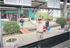  ??  ?? A station master waves his green flag as a sign for the train to take off.