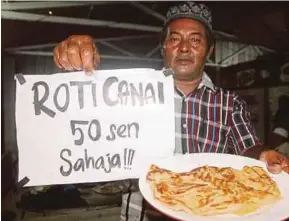  ?? [FOTO NOR AMALINA ALIAS/BH] ?? Abdul Rashid menunjukka­n roti canai dengan harga 50 sen sekeping di gerainya di Kampung Nangka, Bukit Marak, Kota Bharu.