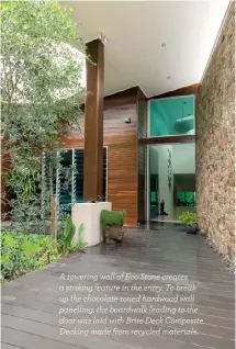  ??  ?? A towering wall of Eco Stone creates a striking feature in the entry. To break up the chocolate-toned hardwood wall panelling, the boardwalk leading to the door was laid with Brite Deck Composite Decking made from recycled materials.