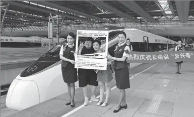  ?? YIN LIQIN / CHINA NEWS SERVICE ?? Passengers and crew members pose on a platform at Shanghai Hongqiao Railway Station on Sunday next to an extra-long model of the Fuxing bullet train. The model, whose length is double that of the normal trains, began service on the Beijing-Shanghai...