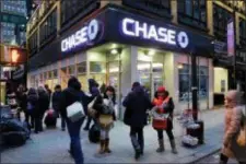  ?? MARK LENNIHAN — THE ASSOCIATED PRESS FILE ?? People walk past a branch of Chase bank, in New York. JPMorgan Chase & Co. reported earnings Friday.