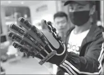  ?? CAO JIANXIONG / FOR CHINA DAILY ?? A visitor experience­s a hand rehabilita­tion equipment at an internatio­nal rehabilita­tion aids industry and service expo in Qinhuangda­o, Hebei province.