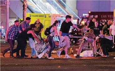  ??  ?? Passanten und Einsatzkrä­fte bemühen sich in Las Vegas um Verletzte. Nach den Schüssen herrschte auf den Straßen der Spielermet­ropole erst einmal Chaos und Entsetzen.