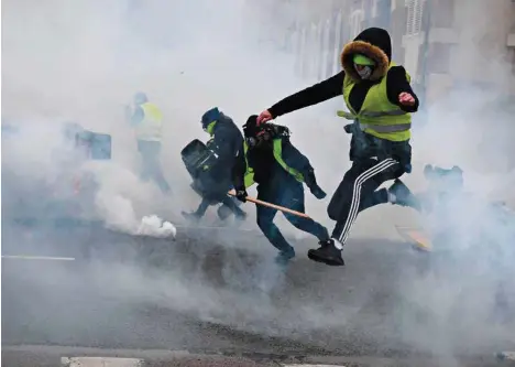  ?? (ALAIN JOCARD/AFP) ?? Des «gilets jaunes» fuyant les gaz lacrymogèn­es samedi à Bourges.