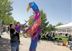  ?? JANE PHILLIPS/FOR THE NEW MEXICAN ?? Cruz Garcia holds Azul Ramirez, 7, as she gives Colleen McKeown with the arts nonprofit Wise Fool a high-five during the fifth annual Rally for Recovery on Saturday at Railyard Park.