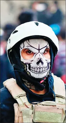  ??  ?? A protester wears a mask during clashes with security forces, in Baghdad, Iraq on Nov 24. At least sixteen people were killed and over 100 wounded in the renewed clashes, which kicked off Thursday as protesters tried to scale a concrete barrier on historic Rasheed Street prompting security forces to fire live ammunition, tear-gas and rubber
bullets to disperse them. (AP)