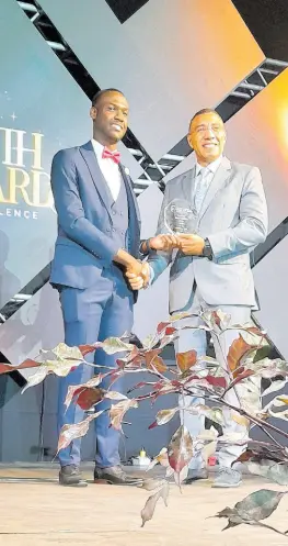  ?? PHOTO BY PAUL H WILLIAMS ?? Evad Campbell receiving his Prime Minister National Youth Award for Excellence in music from Prime Minister Andrew Holness on the evening of Saturday, April 20 on the lawns of Jamaica House.