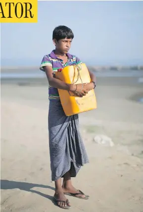  ?? BERNAT ARMANGUE / THE ASSOCIATED PRESS ?? Nabi Hussain, 13, holds the yellow plastic drum he used as a flotation device while crossing the Naf River from Myanmar to Bangladesh.