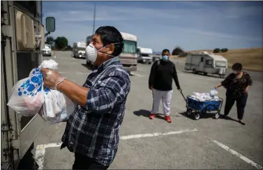  ?? DAI SUGANO — STAFF PHOTOGRAPH­ER ?? RV resident Gregorio Perez gives donated food and essential items, delivered by Reach Potential Movement, to a fellow RV resident on Thursday at one of Shoreline Amphitheat­re’s parking spaces reserved for RV residents in Mountain View.