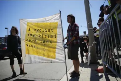  ?? RENÉ JOHNSTON/TORONTO STAR ?? David Oliver and Raymond Yeung hold a sign to alert motorists of a cyclist death during a memorial bike ride on Saturday on Lake Shore Blvd. W. Five-year-old Xavier Morgan died recently after biking on the Martin Goodman Trail and falling into traffic.