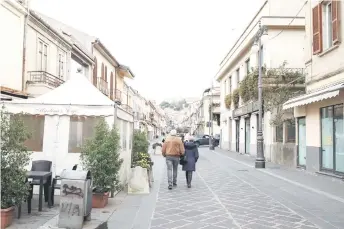  ?? — AFP photos ?? People walk along Corso Vittorio Emanuele III, with the town’s medieval castle in the background in Vibo Valentia, Calabria.