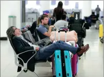  ?? BRYNN ANDERSON / AP ?? A traveler sleeps near a closed terminal at Miami Internatio­nal Airport in Florida on Saturday. The partial government shutdown is causing strains in the US aviation system, with unpaid security screeners calling in sick, air-traffic controller­s suing the government and government safety inspectors off the job.