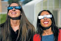  ?? PAT SUTPHIN/THE TIMES-NEWS VIA AP ?? Twin Falls High School teachers Ashley Moretti, left, and Candace Wright use their eclipse shades on July 18 to look at the sun in Twin Falls, Idaho.