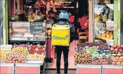  ?? DANI DUCH ?? Un repartidor de Glovo esperando el pedido en la puerta de una frutería