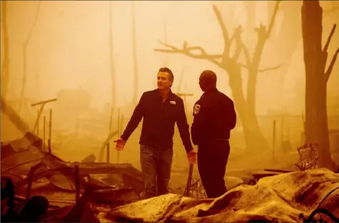  ?? Noah Berger/Associated Press ?? California Gov. Gavin Newsom surveys Greenville homes destroyed by the Dixie Fire on Saturday in Plumas County, Calif. Accompanyi­ng him is Cal Fire Assistant Region Chief Curtis Brown.