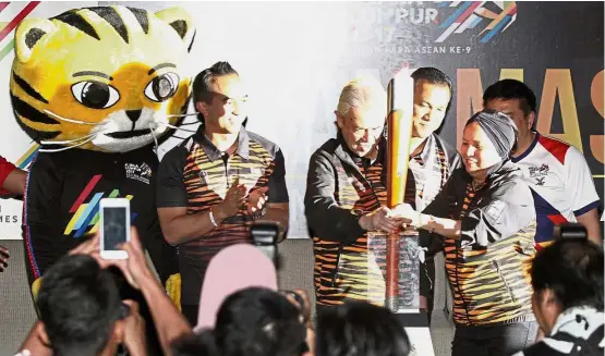  ??  ?? All set for the Games: Abdullah and his wife Jeanne holding the Para Asean Games torch after receiving it from the Malaysian contingent. Looking on is SM Nasarudin (left).