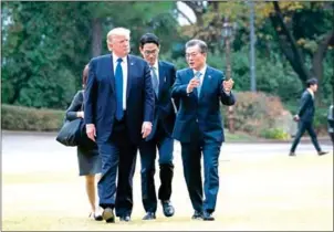  ?? MILLS/THE NEW YORK TIMES DOUG ?? President Donald Trump is escorted by President Moon Jae-in of South Korea during a walk on the grounds of the Blue House, the presidenti­al residence in Seoul, on November 7.