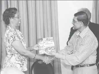  ?? (Photo by Keno George) ?? Editor of the Guyana Annual Petamber Persaud (right) presenting a copy of the latest publicatio­n to a representa­tive of the National Library.