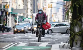  ?? MICHAEL NAGLE/ BLOOMBERG ?? A Doordash bike messenger makes a delivery in New York in December. Lawmakers in many states temporaril­y relaxed regulation­s to make alcohol available for home delivery during the pandemic.