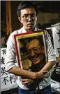  ?? LAM YIK FEI / THE NEW YORK TIMES ?? A man mourning dissident Liu Xiaobo’s death clutches a photo of Liu on Thursday during a demonstrat­ion in Hong Kong.