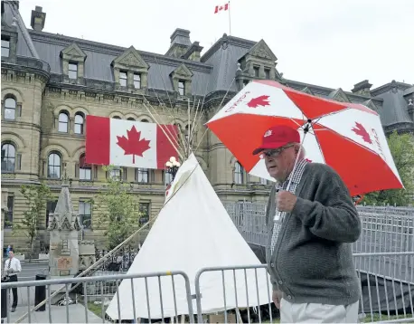  ?? JUSTIN TANG/THE CANADIAN PRESS ?? The Office of the Prime Minister and Privy Council is seen behind as a man walks past a large teepee erected by indigenous demonstrat­ors to kick off a fourday Canada Day protest in front of Parliament Hill on Thursday.