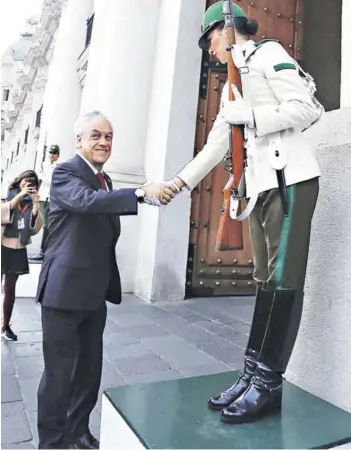  ??  ?? ► Piñera saludando ayer a las nuevas centinelas del Palacio de La Moneda.